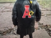 A close up shot of Ace's back, showing off the details on the back of her jacket. The only detail is her name 'Ace' with the A in red and the c and e in yellow