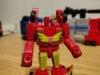 Hot Rod in robot mode, a very simple design. Predominantly red, his flame hood has become his chest and - while mostly off image - the rear of the vehicle has formed his legs (parts of the spoiler are visible in the image)