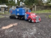 Legacy Armada Optimus Prime in vehicle mode, a red truck with a blue with grey highlights trailer, instead of having wheels, the trailer has treads