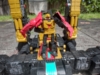 Legacy BlackZarak's Headmaster, standing on the center of his transtector's base mode, with one hand on his hip