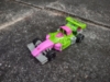 Legacy G2 Mirage in vehicle mode, a green and pink Formula One racecar with an alligator motif.