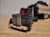RID Scourge in vehicle mode, a black long-nose truck with teal highlights and red windows hauling a silver oil tanker trailer.